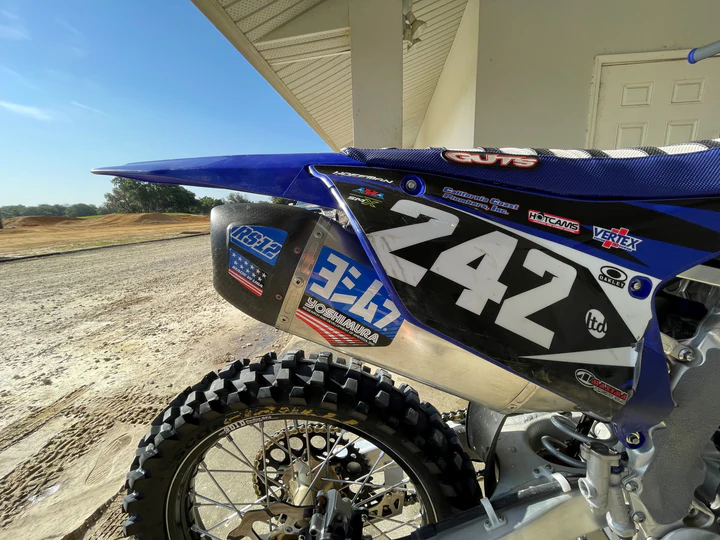 YOSHIMURA RS12 muffler decals in blue on high-performance motorcycle exhaust part, featuring bold YOSHIMURA branding.