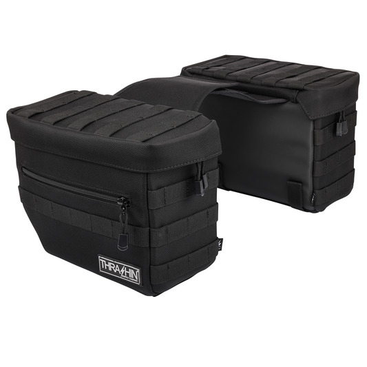 Black THRASHIN SUPPLY CO. Essential Saddlebags with 10-liter capacity, shown mounted on motorcycle for storage.