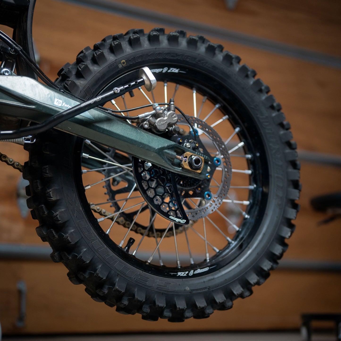 Warp9Racing Ultra Disk Guard rear disc brake guard for motorcycles, shown on a bike in black with mounting hardware.