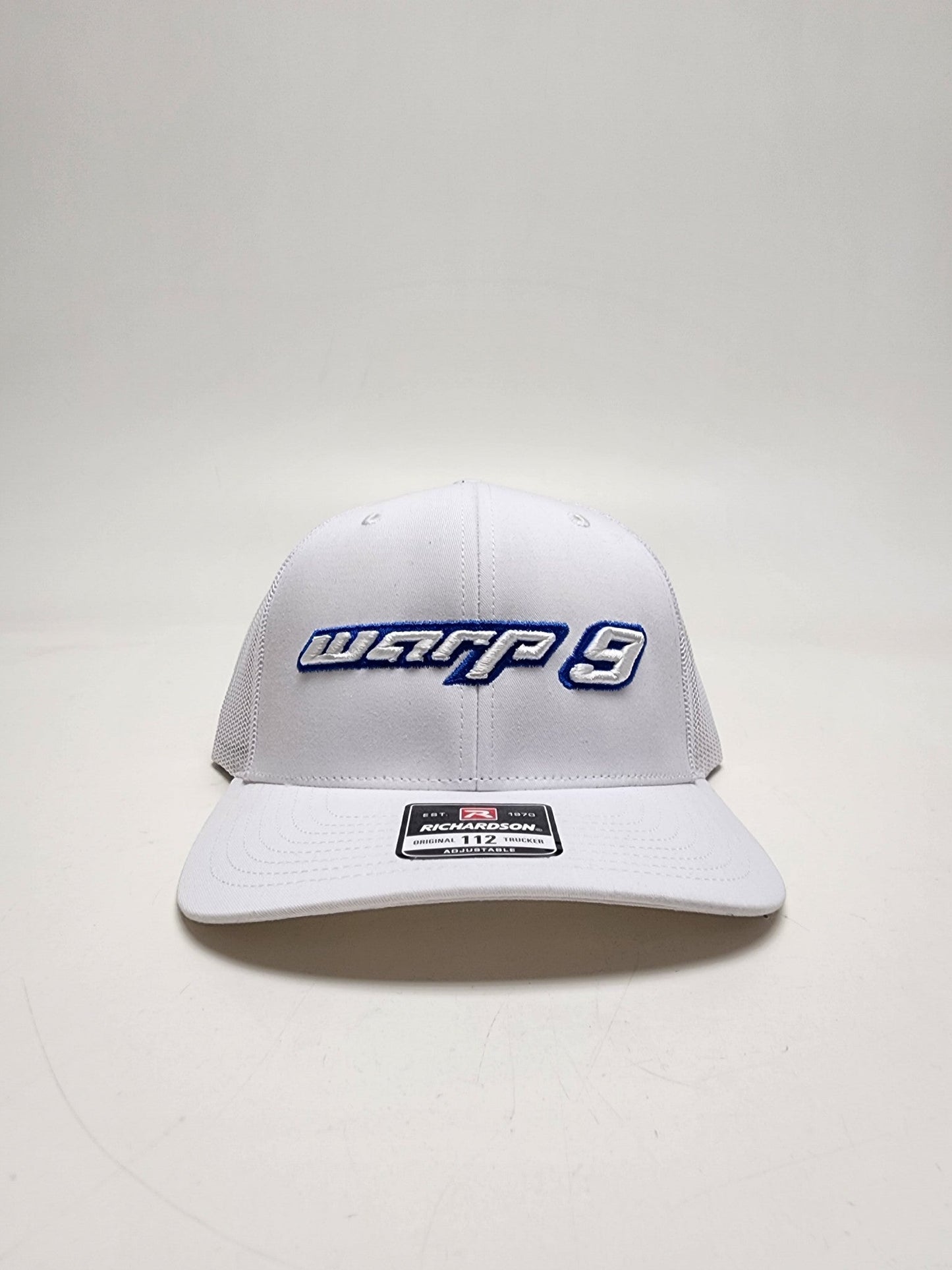 White and blue WarpWear W9 hat with adjustable strap and embroidered Warp9Racing logo, stylish apparel for racing fans.