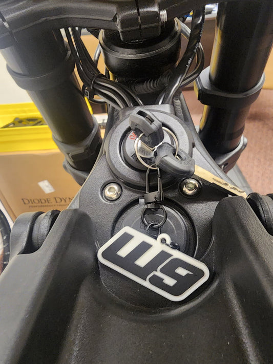 Warp9Racing rubber keychain featuring apparel-themed design, durable and colorful accessory for fans and enthusiasts.
