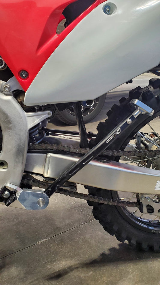 Warp9Racing Honda CRF add-on kickstand mounted on motorcycle, showcasing durable black metal construction for secure parking.