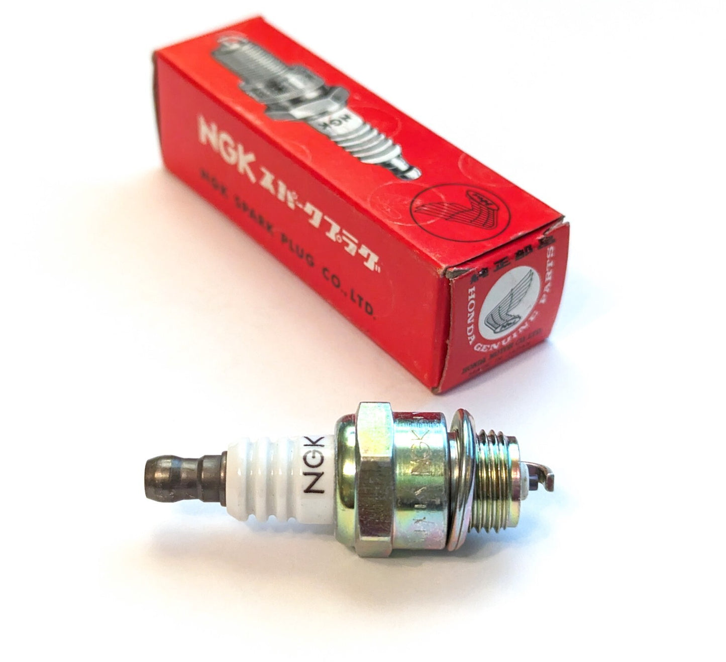 NGK Spark Plugs BPM4A-10 Honda OEM spark plug showing the metal shell and ceramic insulator in a close-up image.