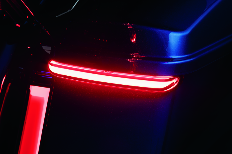 Kuryakyn Tracer Saddlebag Lights with red lens mounted on Harley Davidson touring motorcycle for enhanced visibility and style.