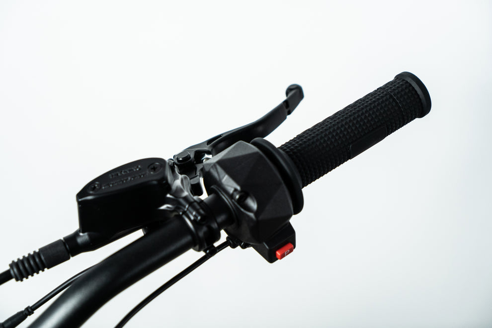 Howling Moto Grasshopper SE electric dirt bike with 72V 60Ah battery and 12.5kW mid-drive, shown outdoors on rugged terrain.