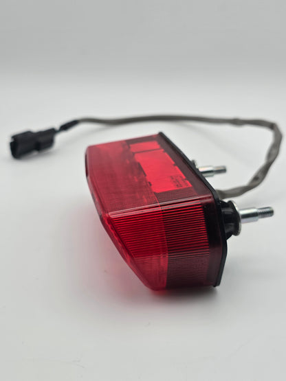 Used Honda Grom OEM tail light for 2014-2015 models, motorcycle lighting part in good condition, black housing with clear lens.