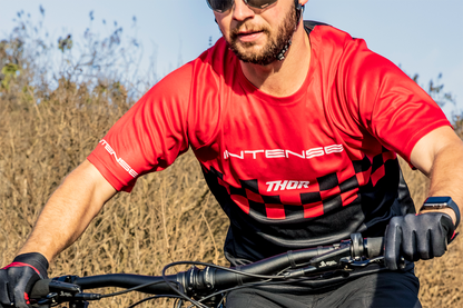 Red and black THOR Intense Assist Chex MTB short-sleeve jersey, medium size, designed for e-MTB and mountain biking performance.