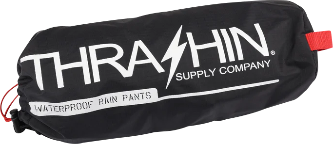 Black Thrasin Supply Co. Mission rain pants in size S/M laid flat showing the waterproof fabric and slim fit design.