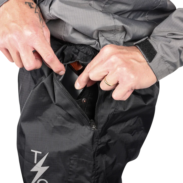 Black THRASHIN SUPPLY CO. Mission Rain Pants in size S/M laid flat showcasing the waterproof fabric and adjustable waistband.