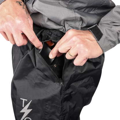 Black THRASHIN SUPPLY CO. Mission Rain Pants in size S/M laid flat showcasing the waterproof fabric and adjustable waistband.