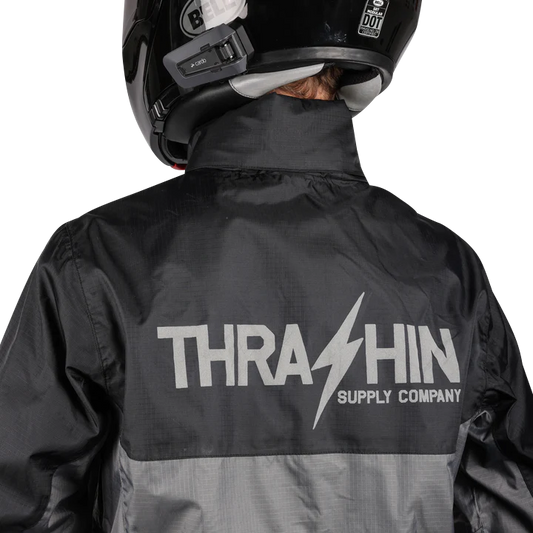 Black and gray THRASHIN SUPPLY CO. Mission WP Rain Jacket in XL, shown on a model with hood and waterproof fabric.