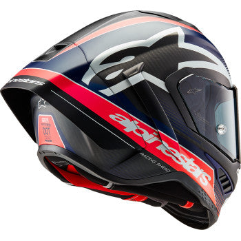 Alpinestars Supertech R10 Team helmet in matte black, carbon red fluo, and blue, shown in a side view on a motorcycle rider.
