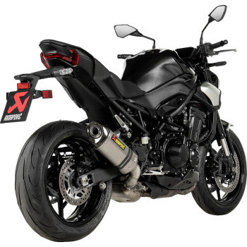 A Kawasaki Z900 2025 motorcycle with a titanium Akrapovic slip-on exhaust muffler, showcasing sleek metal finish and branding.