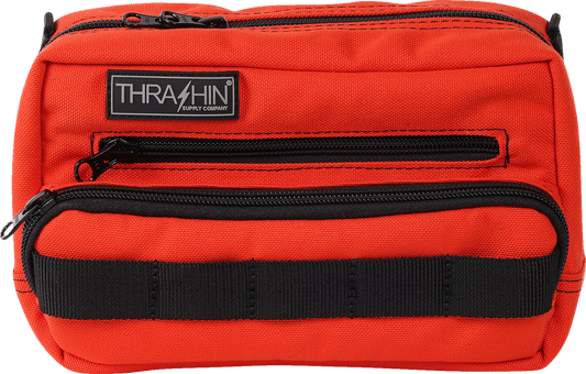 Orange THRASHIN SUPPLY CO. Handlebar Bag Plus mounted on a bicycle handlebar, showing its compact, durable design.