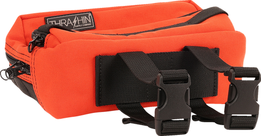 Orange THRASHIN SUPPLY CO. Handlebar Bag Plus mounted on a bike handlebar, featuring a durable, compact design for cycling essentials.