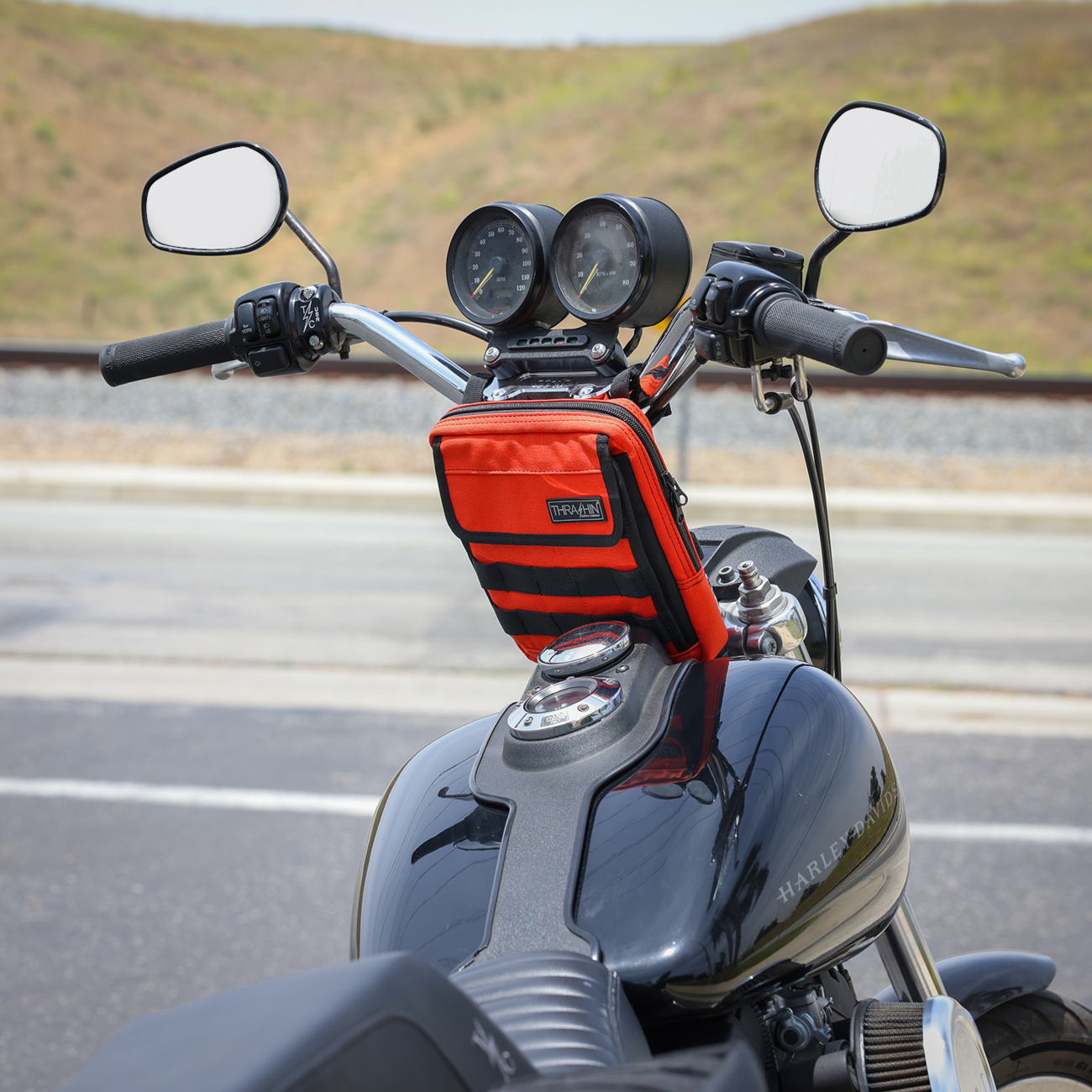 Orange handlebar bag from THRASHIN SUPPLY CO., Slim design with secure strap attachment for bicycles.