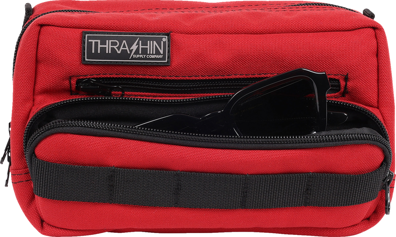 Red Thrashin Supply Co. Handlebar Bag Plus mounted on a bicycle handlebar, featuring durable straps and compact design.