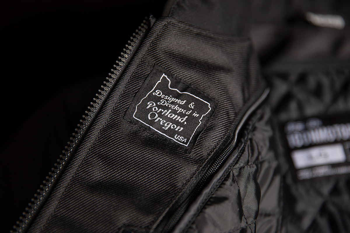 Black ICON Motorhead3™ jacket by Bill's Exhausts, large size, featuring a sleek design and durable fabric, shown on a hanger.