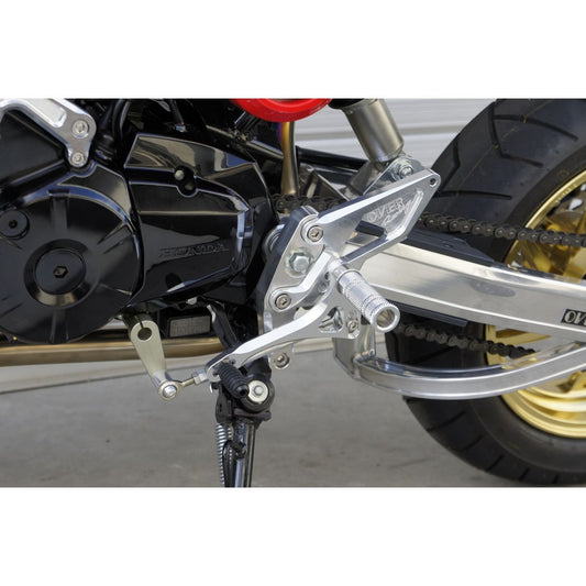 Over Racing 4-position rearsets for Honda Grom motorcycle, featuring metallic footpeg and adjustable mounting points.