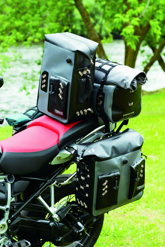 Kuryakyn Torke 25L dry waterproof motorcycle backpack with reflective logos and versatile storage options, shown outdoors.