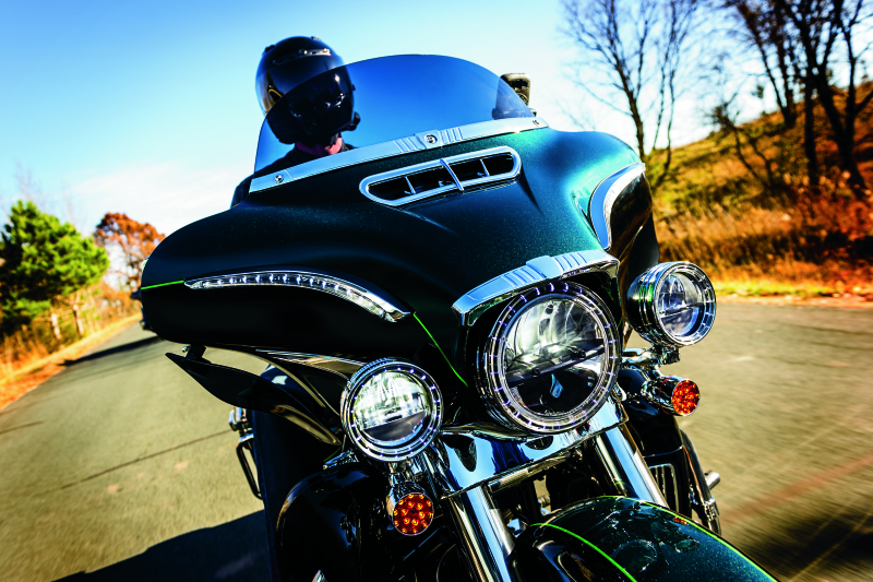 Chrome Kuryakyn Tri-Line Windshield Trim on a Harley Davidson Touring motorcycle, showcasing sleek, polished design.