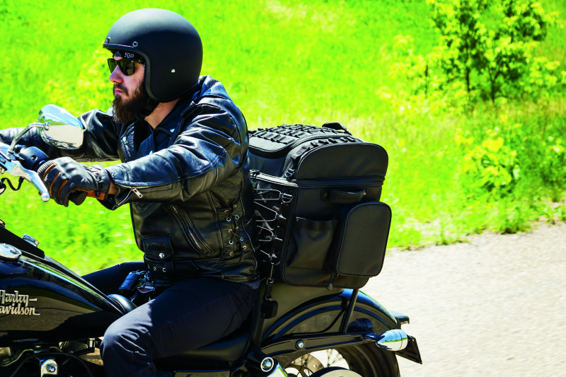 Kuryakyn Momentum Vagabond Bag attached to motorcycle seat and luggage rack for versatile storage.