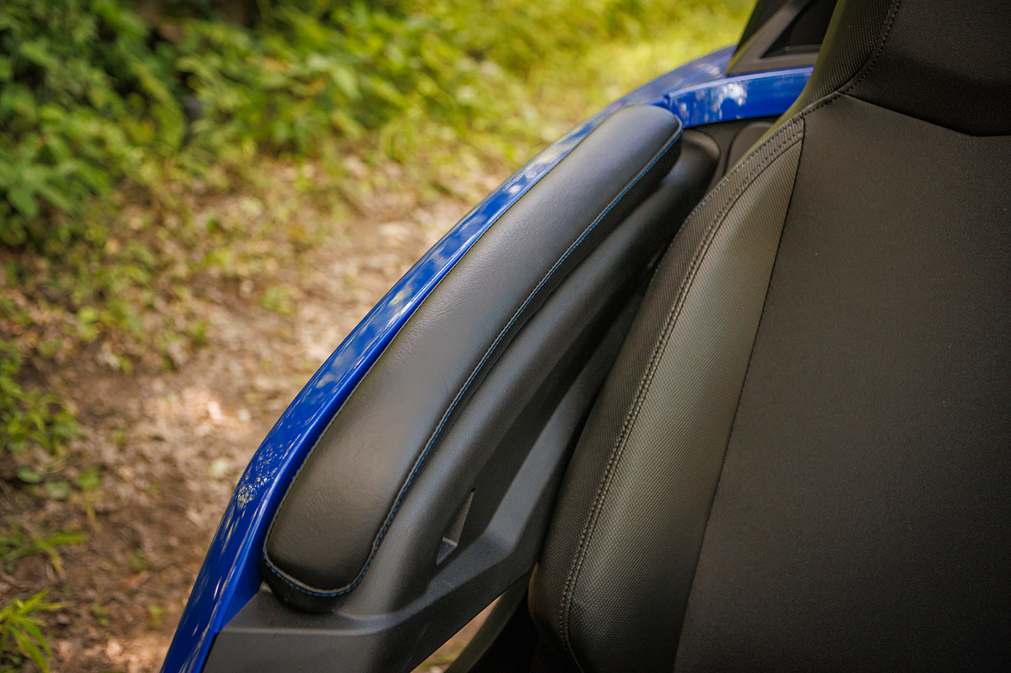 Black SHOW CHROME Kaliber Armrest Pads with blue stitching for Slingshot 2015-2022 engine, designed by Bill's Exhausts.