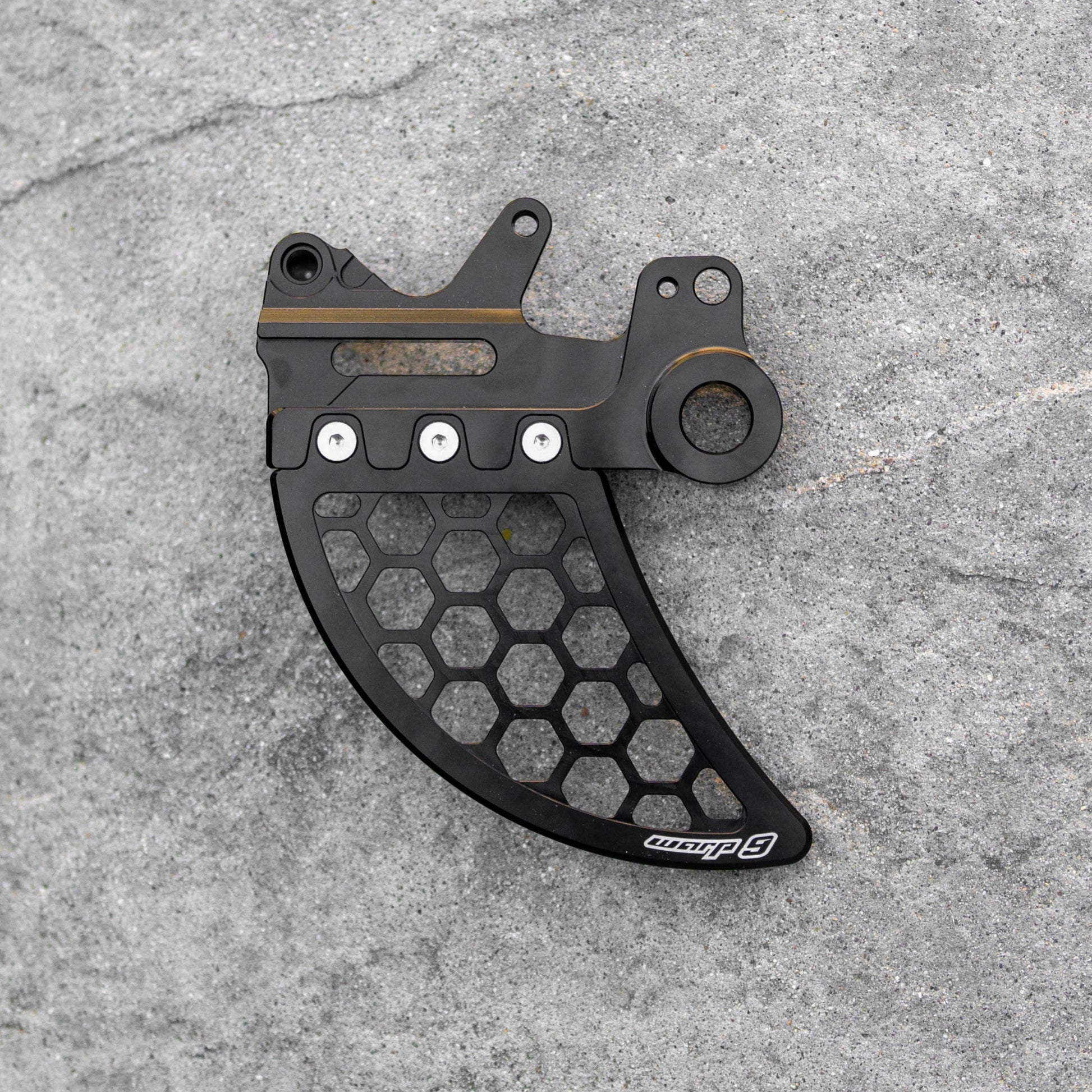 Warp9Racing Ultra Disk Guard rear disk guard installed on motorcycle wheel, protecting the brake disc from debris and damage.