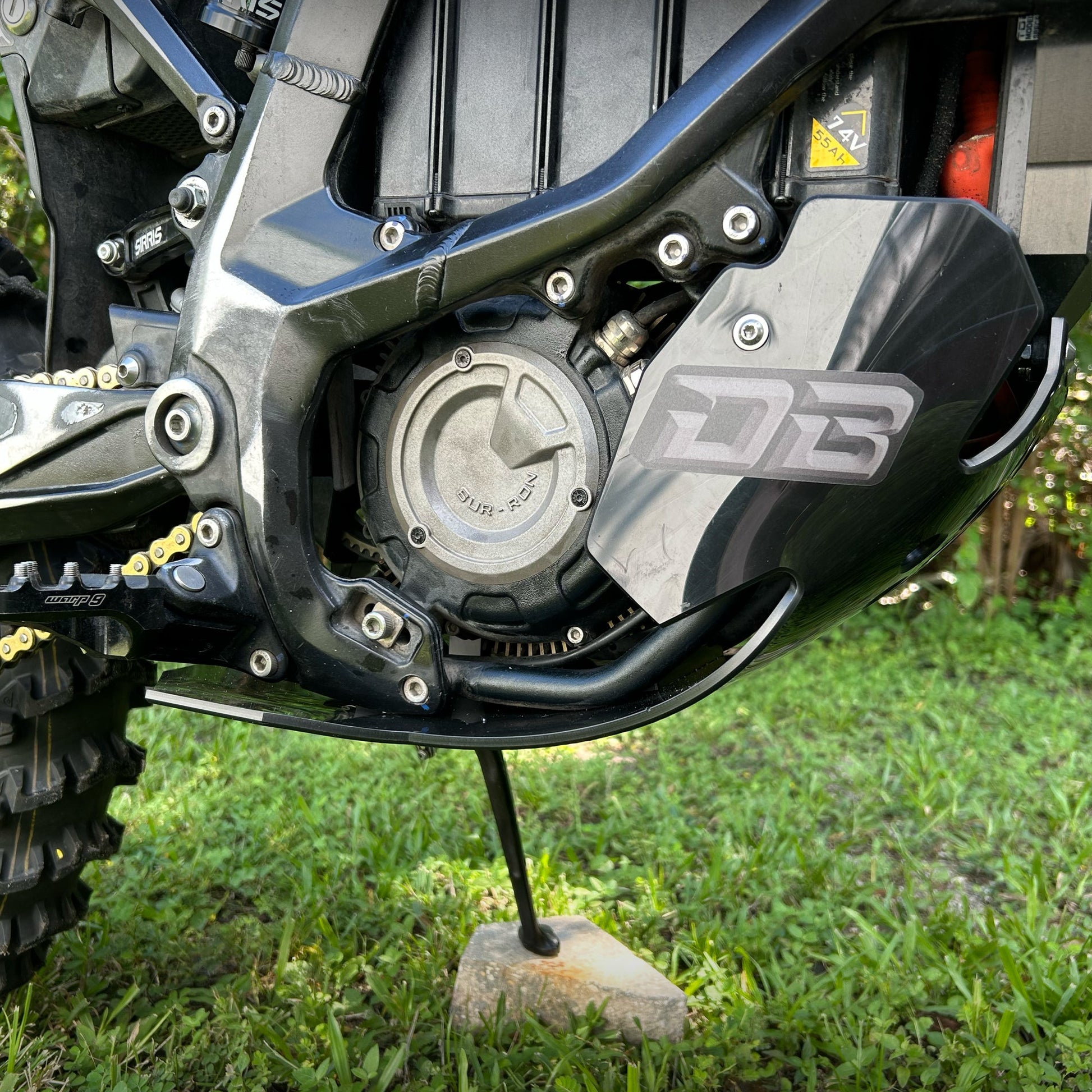 Surron Ultra Bee eDirtyBike skid plate installed on bike, close-up view showing protective metal underframe for off-road riding.