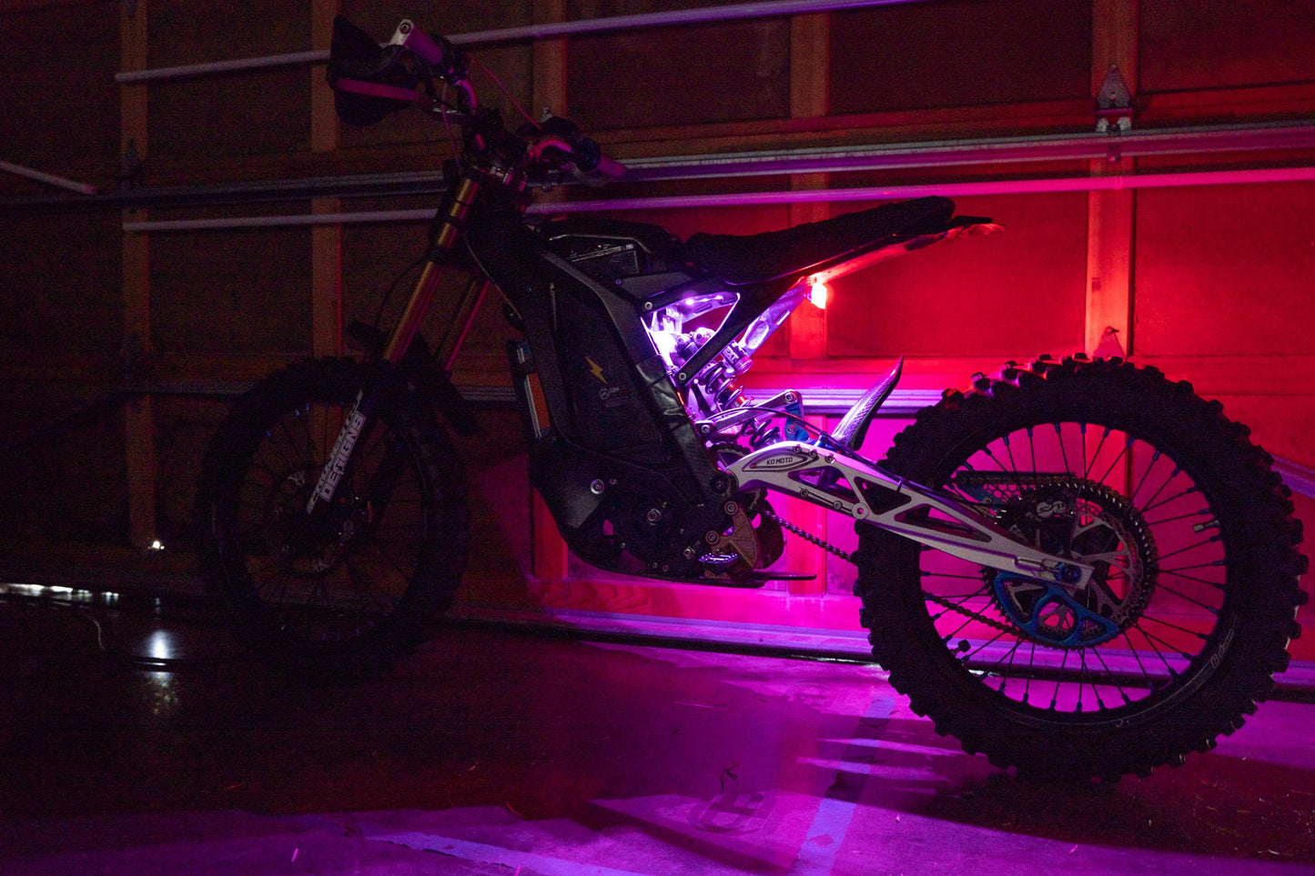 Purple Surron underglow kit by Project9, featuring vibrant LED lights illuminating the underside of the Surron electric bike.