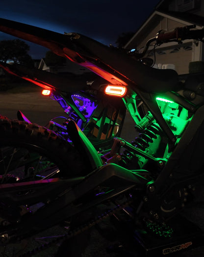 Purple and green Surron underglow kit from Project9 with cyber V2 tail light, installed on a Surron electric bike.