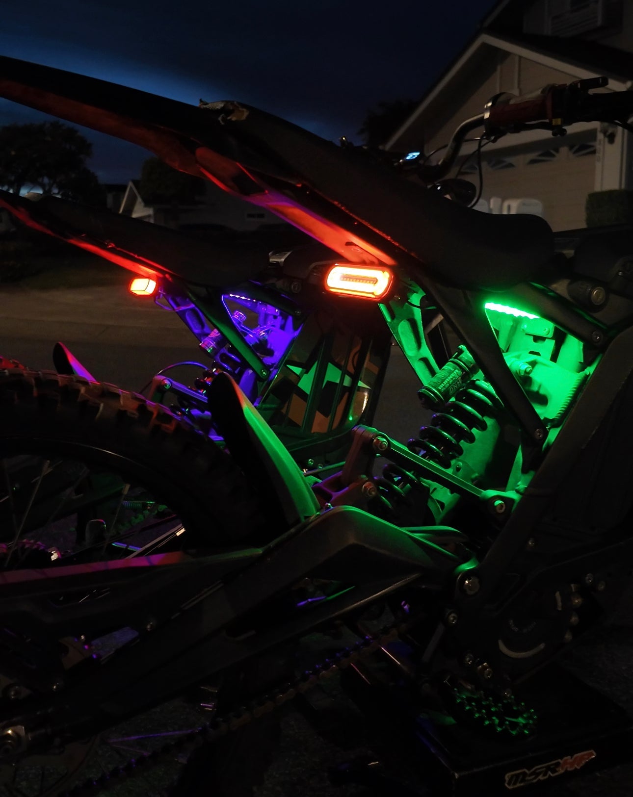 Purple and green rear underglow kit for Talaria MX4 and MX5 bikes by Project9, showing illuminated LED lights on the motorcycle.