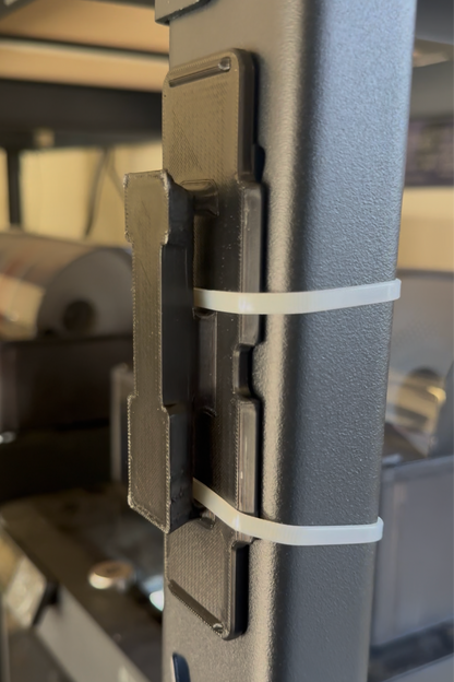 Universal mount plate accessory by McCoy Industries, showing a flat metal mounting plate with screw holes for versatile use.