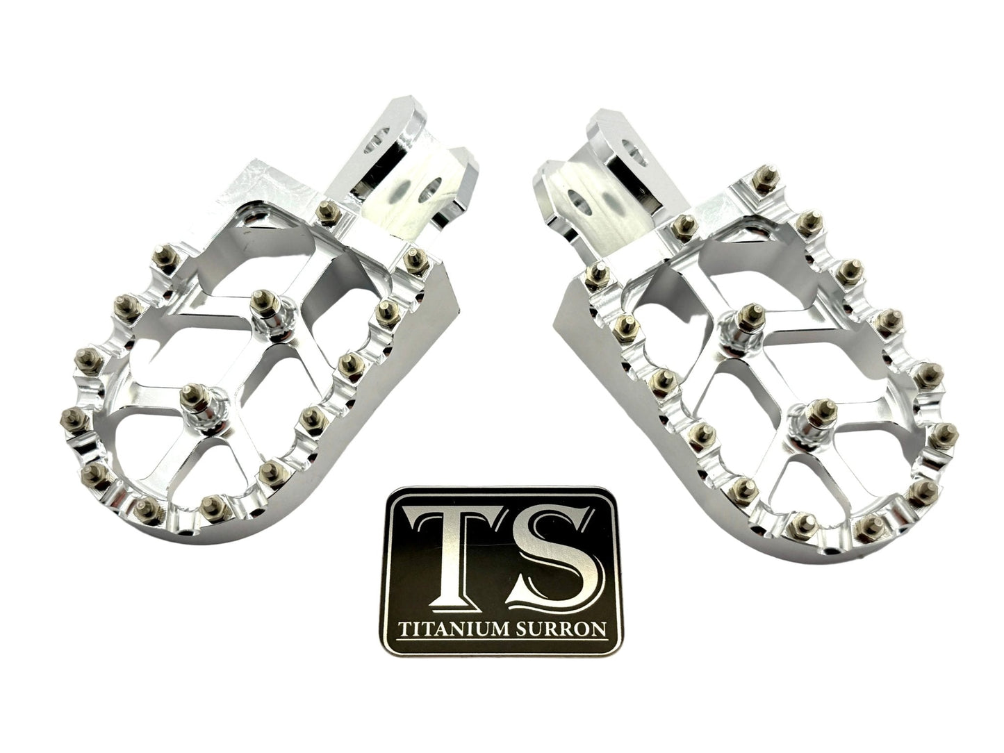 Anodized aluminum 6061 TS foot pegs by Titanium Surron for Surron and similar e-moto, showing textured surface and mounting points.