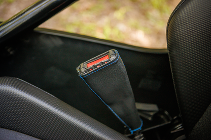 Black SHOW CHROME seat belt covers with blue stitching, designed for engine safety and comfort by Bill's Exhausts.