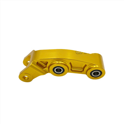Gold CNC aluminum suspension linkage for Surron LBX eDirtyBike electric bike, detailed close-up of the high-quality component.