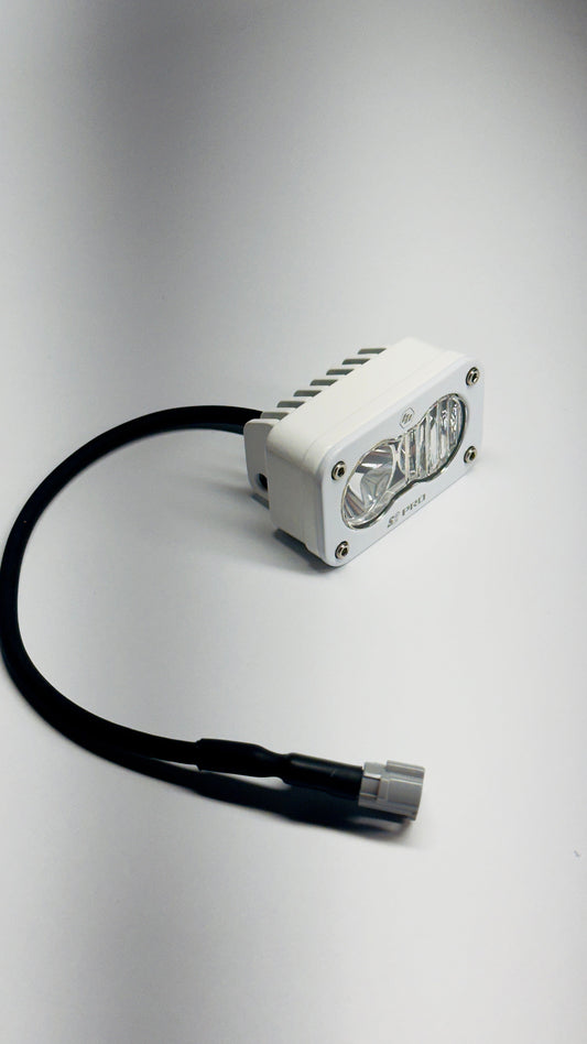 Elektrisches Racing Baja Designs S2 Pro White LED light with pre-wiring for Surron electric bike, mounted on bike frame.