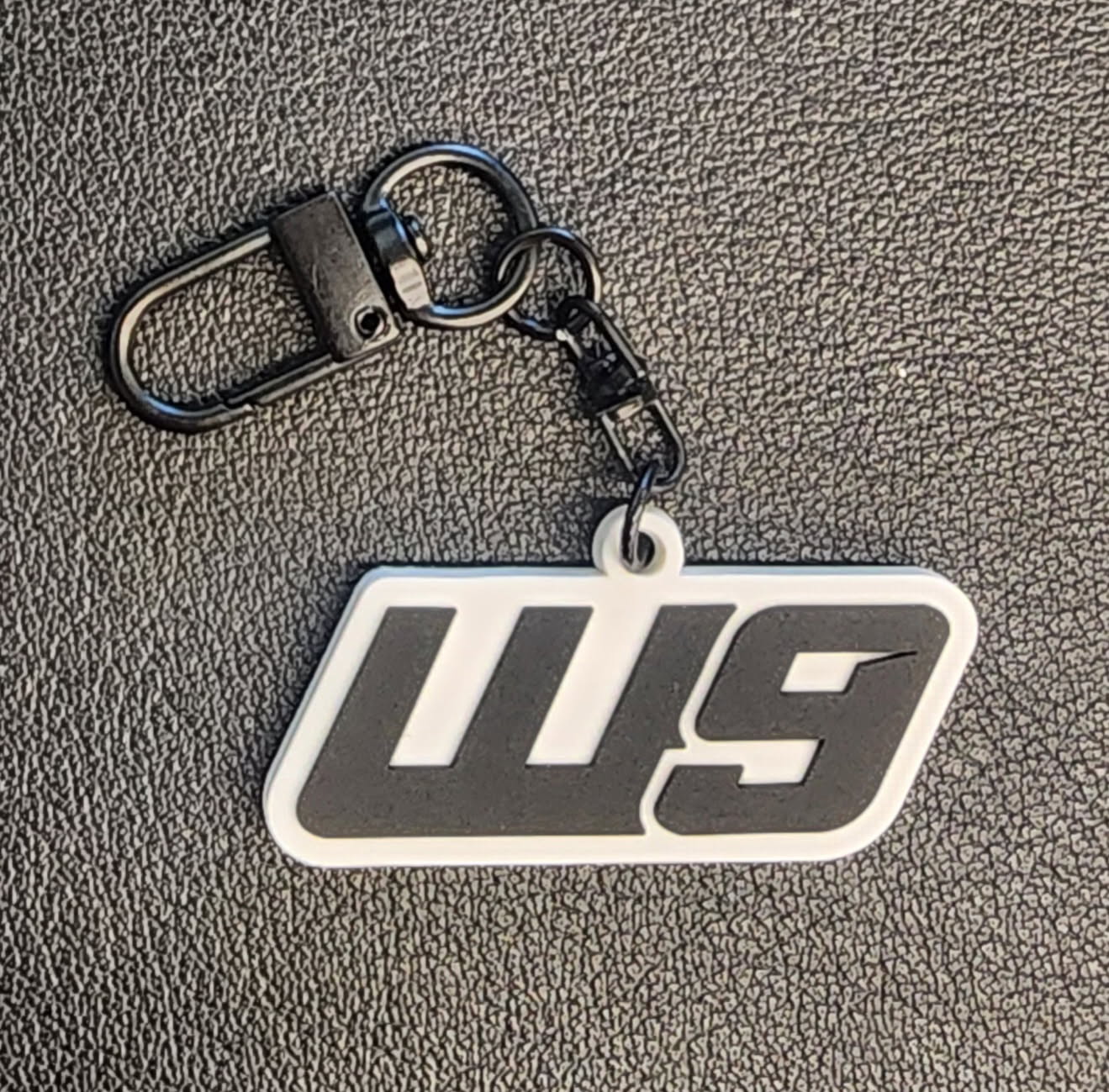 WarpWear rubber keychain featuring bold Warp9Racing branding, attached to colorful apparel accessories.