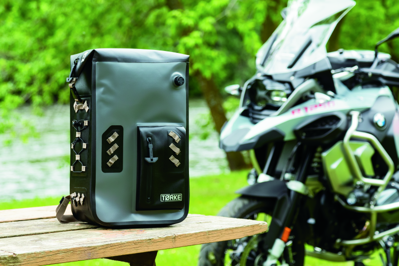 Kuryakyn Torke 25L waterproof motorcycle backpack with reflective logos and versatile storage, shown on a motorcycle rider.