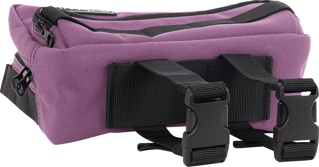 Purple THRASHIN SUPPLY CO. Handlebar Bag Plus mounted on a bicycle handlebar, featuring durable design and secure strap attachments.