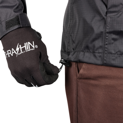 Black THRASHIN SUPPLY CO. Mission WP Rain Jacket in medium size, shown on a hanger with front zipper and hood.
