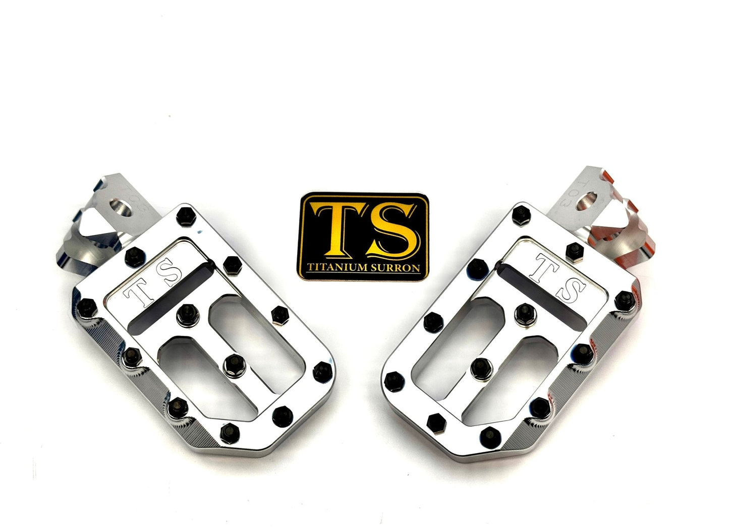 Titanium Surron custom foot pegs with titanium grips for Surron and light e-moto, shown installed on a motorcycle.