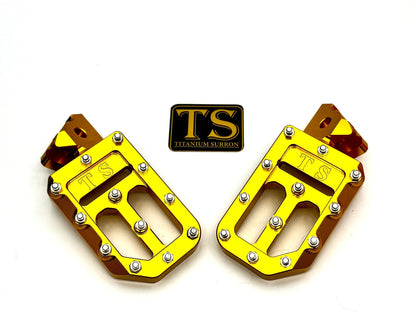 Titanium Surron custom foot pegs with titanium grips for Surron and light e-moto bikes, featuring sleek metal design.
