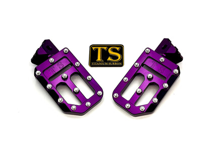 Titanium Surron custom foot pegs with titanium grips for Surron and light e-moto bikes, featuring sturdy metal construction.