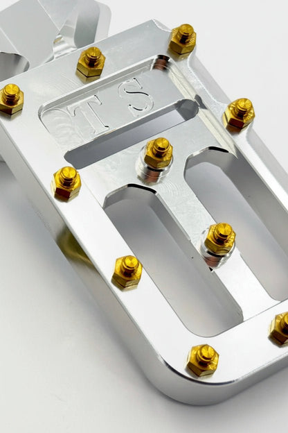 Titanium Surron custom foot pegs with titanium grips for Surron and light e-moto, featuring durable metallic construction and grip details.