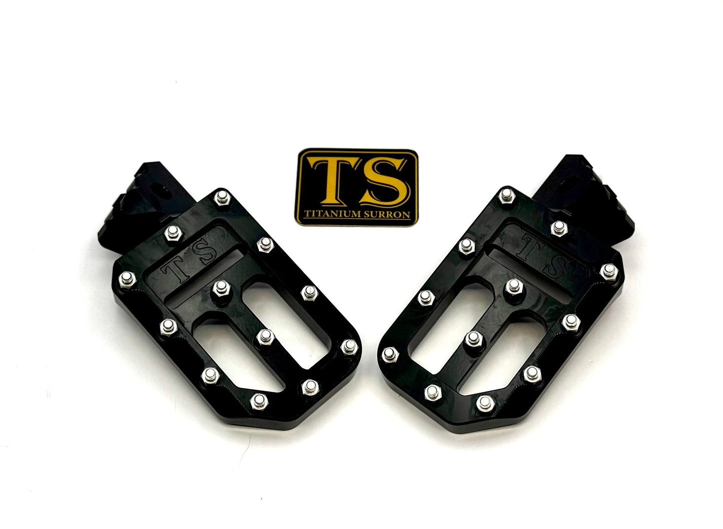 Titanium Surron custom foot pegs with titanium grips, designed for Surron and light e-moto bikes, shown mounted on the bike.