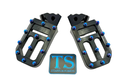 Titanium Surron custom foot pegs with titanium grips for Surron and light e-moto bikes, featuring durable metallic finish.
