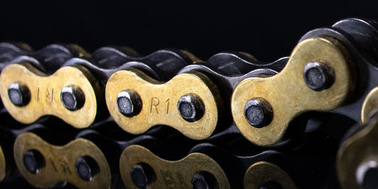 Warp9Racing Renthal R1 Works 520 motorcycle chain with silver links and branding, shown in a close-up view.