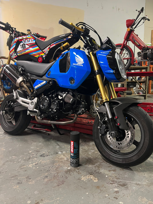 Motul Shine & Go Plastic and Paint Detailer Spray showing a spray bottle with clear liquid on car surface for detailing.